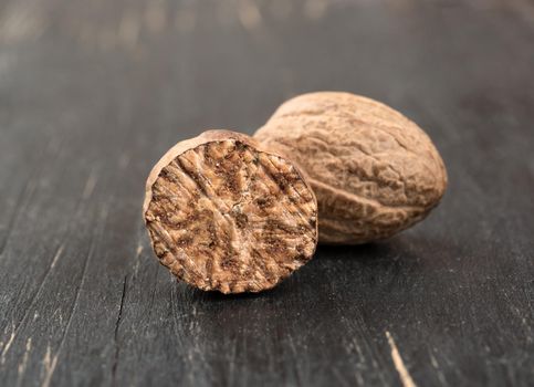Dry nutmeg with half on wooden background