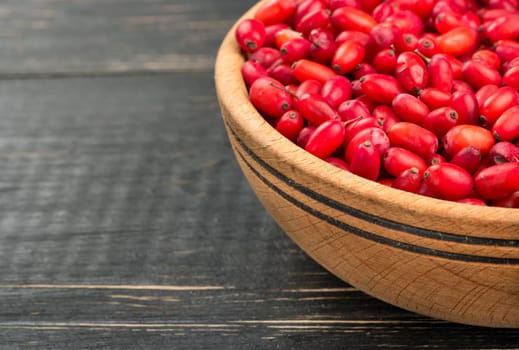 Part of the barberry bowl on wooden background closeup