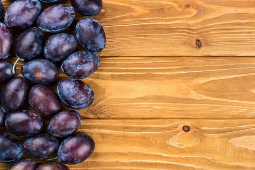 Fresh blue plums on a blank wooden background