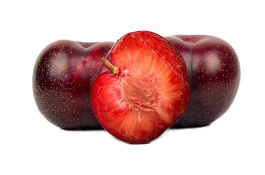 Large red plum with juicy half on white background