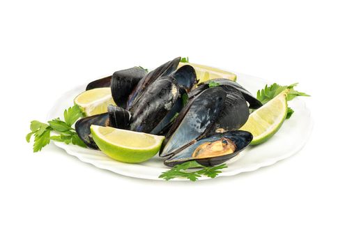 Plate with a pile of cooked mussels with lime and parsley on a white background