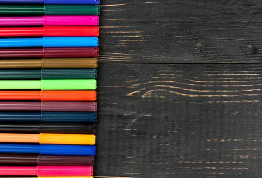 Lot of colorful markers on wooden background, top view