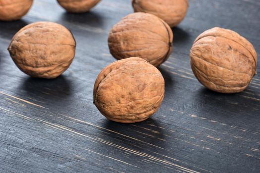 Scattered walnuts in shell on wooden background