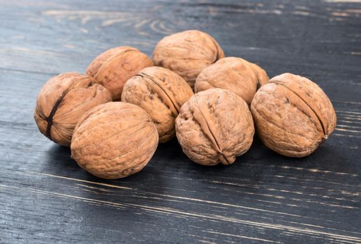 Several inshell walnuts on a dark table closeup