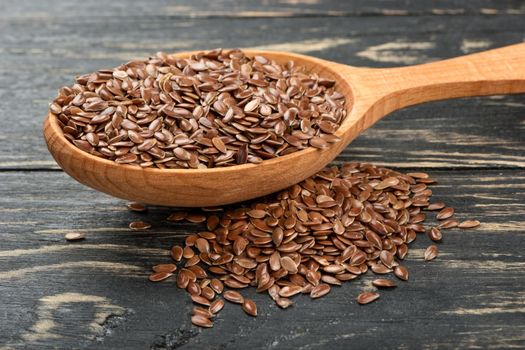 Spoon with flax seed and scattered grain on the table closeup