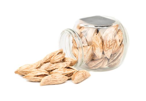 Scattered uzbek almonds from a jar isolated on white background