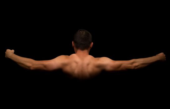 Beginner bodybuilder shows his back and hands on a black background
