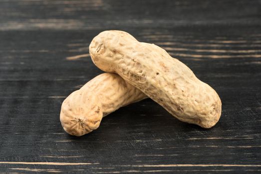 Two peanuts in shell closeup on a wooden background