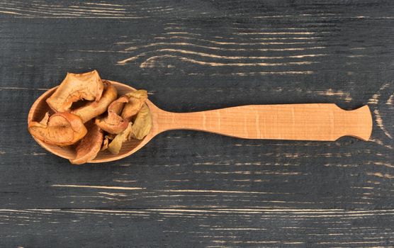 Slices of dried apples in a spoon on wooden background top view