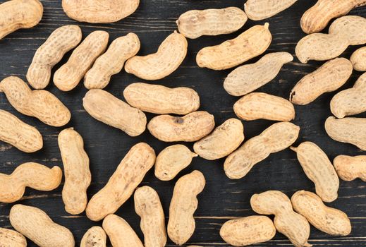 Scattered peanuts in the shell on wooden background, top view