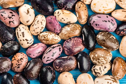 Diffuse dry colored kidney bean on a wooden background, top view