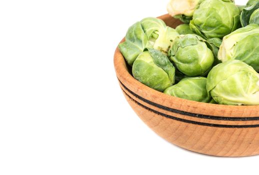 Part of a bowl of fresh brussels sprouts on a white background