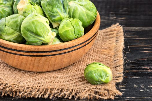 Bowl with raw brussels sprouts on sackcloth and table closeup