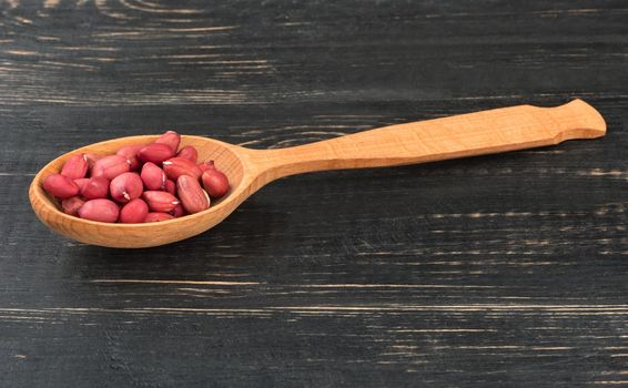 Kernel dry peanut in the spoon on wooden background
