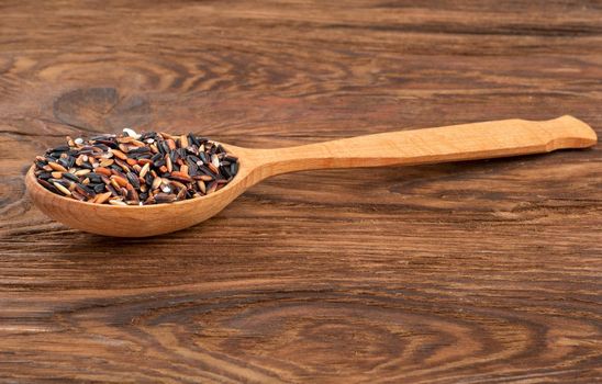 Raw wild rice in a spoon on the table close-up