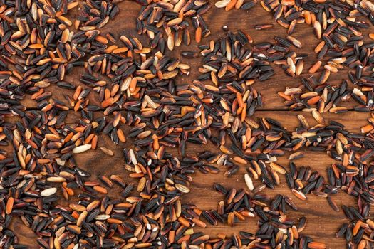 Scattered black wild rice on wooden background, top view