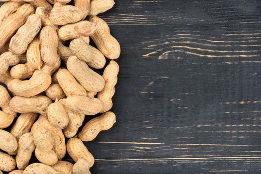 Scattered peanuts in the shell on an empty wooden background