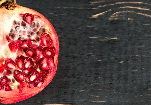 Part of half a pomegranate on a dark table closeup