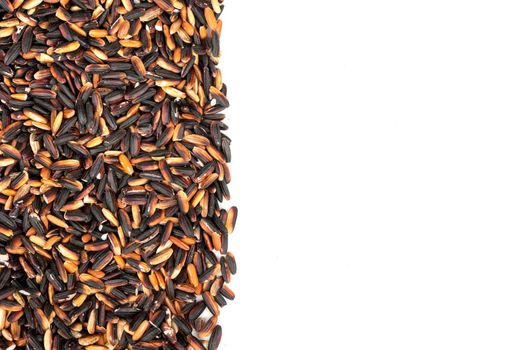 Scattered raw black rice on white background, top view