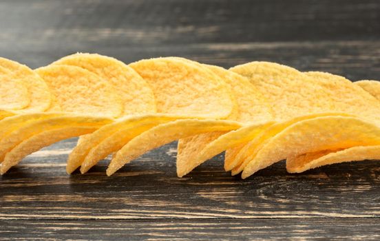 Scattered potato chips on a dark table closeup