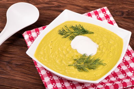 Vegetarian cream soup with vegetables in a bowl with scoop on a towel on the table