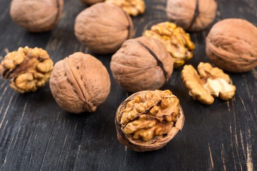 Scattered walnuts in shell and without on wooden background