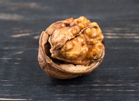 Open a walnut on wooden background closeup