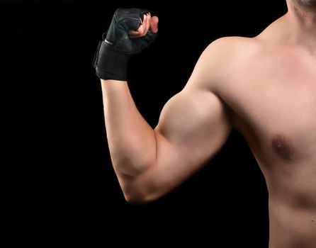 Beginner bodybuilder demonstrates his biceps on black background