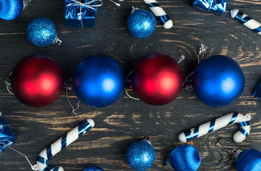 Christmas balls with different decorations on wooden background, top view