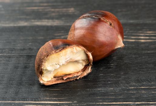 Roasted chestnuts with delicious half on a wooden background