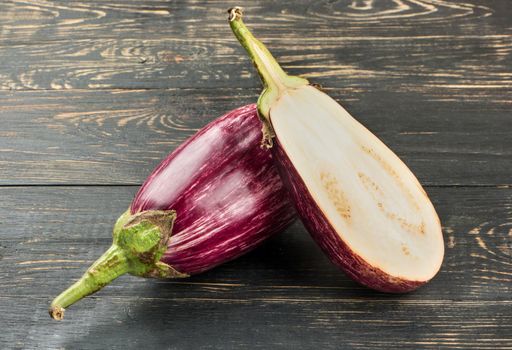 Raw eggplant graffiti with half on wooden background