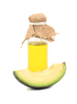 Avocado oil in a bottle with a slice on white background