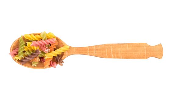 Wooden spoon with colored pasta fusilli on white background, top view