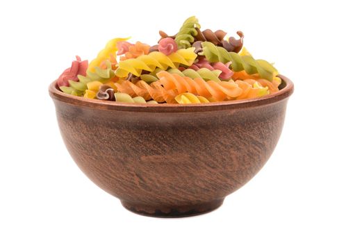 Raw colored pasta fusilli in a bowl on white background