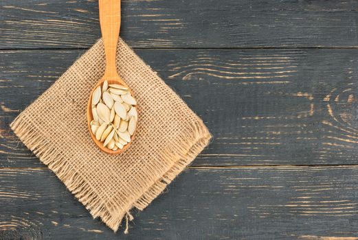 Pumpkin seeds in shell on burlap on wooden background