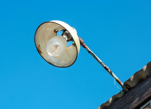 Old street lamp on the roof of the house against the sky