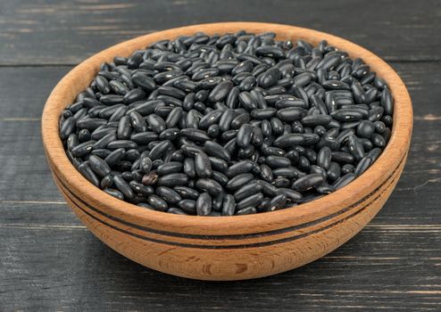 Bowl with black beans on a dark table, close-up