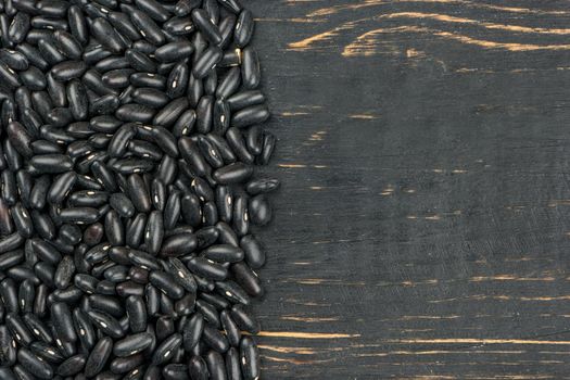 Scattered black beans on wooden background, top view