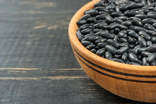 Part of the bowl with black beans on the table close-up