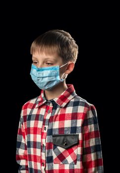 Sick boy in a medical mask on a black background