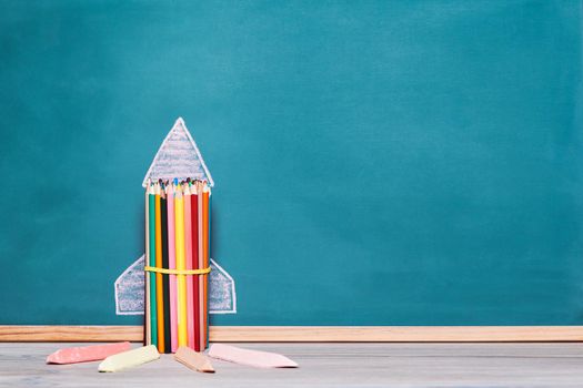 rocket made with crayons and drawn on a blackboard with copy space for text, concept of imagination and back to school