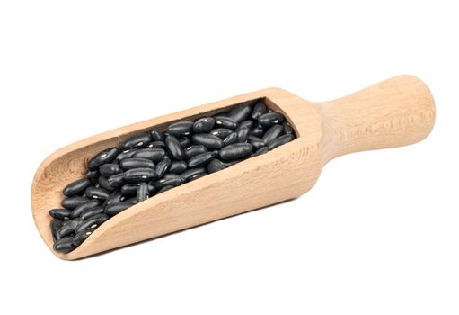 Wooden scoop with black beans isolated on white background