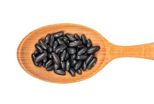 Large wooden spoon with black beans on white background, top view