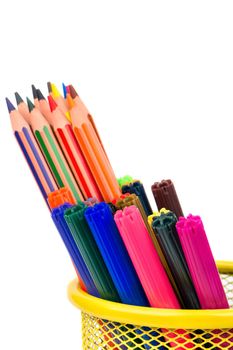 Colored pencils and markers in a basket closeup on white background