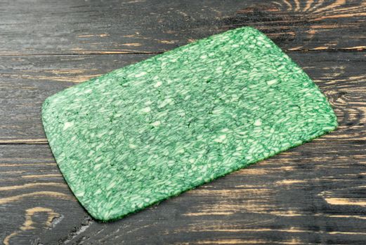 Slice of green cheese with Basil on a dark table