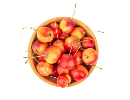 Paradise apples in wooden bowl on white background, top view