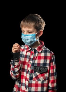 Sick boy in medical mask coughs on black background