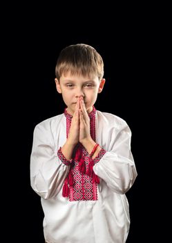 Praying boy in traditional Ukrainian clothes on a black background