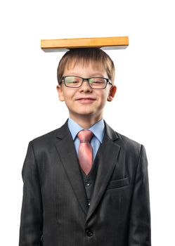 Schoolboy with glasses holds a book on his head on a white background