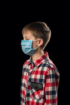 Sick boy in a medical mask on a black background